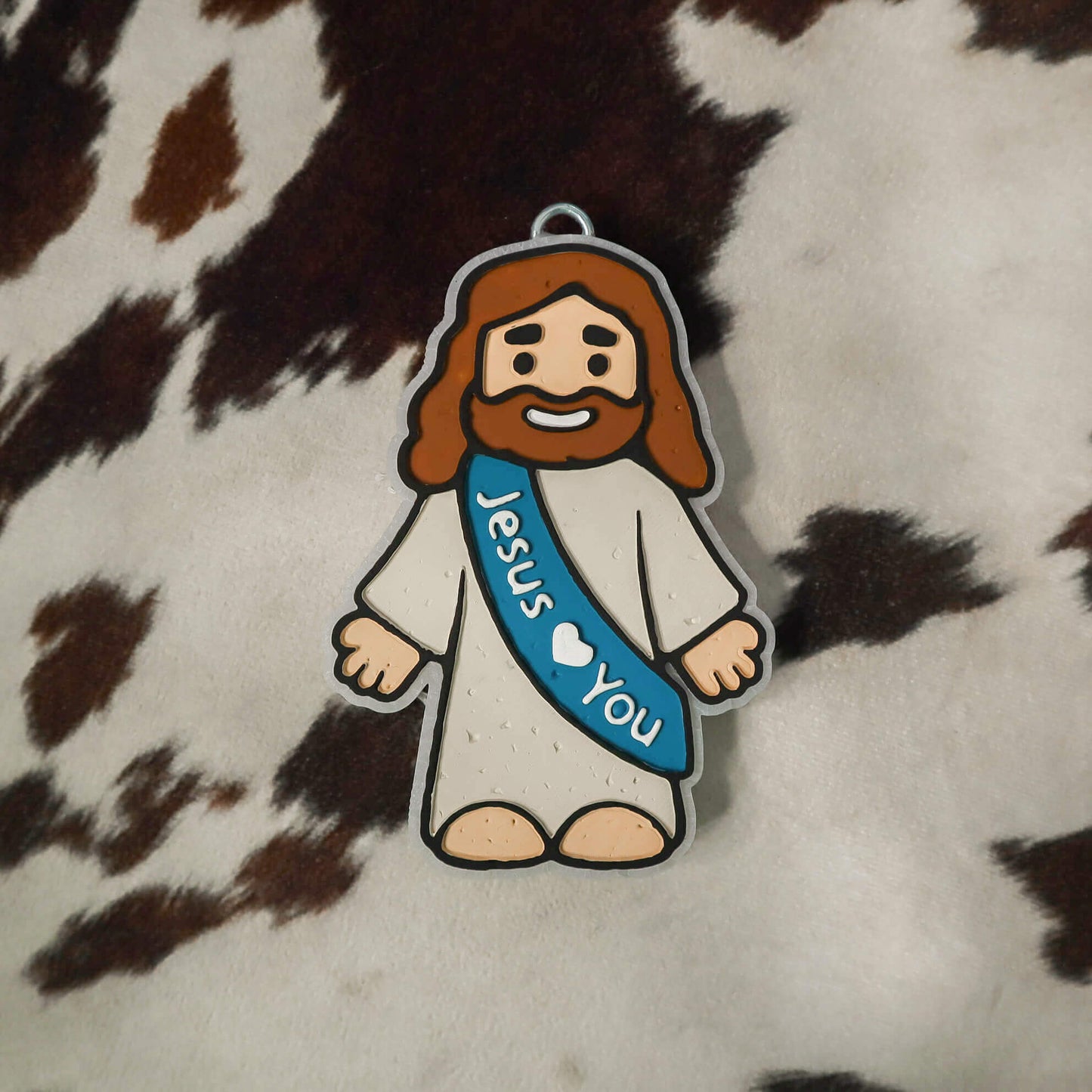 Cartoon character of a bearded figure with a 'Jesus Loves You' sash on a cowhide background